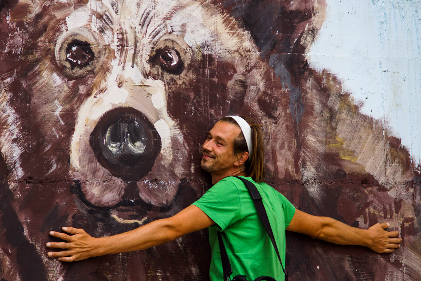 Es ist ein übergroßer Bär an eine Wand im Bären Sanatorium in der Nähe von Pristina gemalt. Paul lehnt sich an die Wand und umarmt den Bären lächelnd