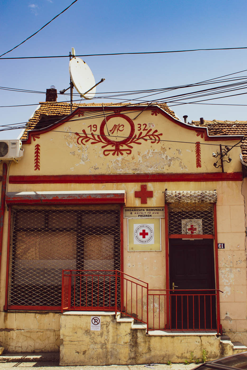 Ein altes Haus von 1932 mit Roten Kreuz Schild und roten Fenster Türrahmen und Treppengeländer