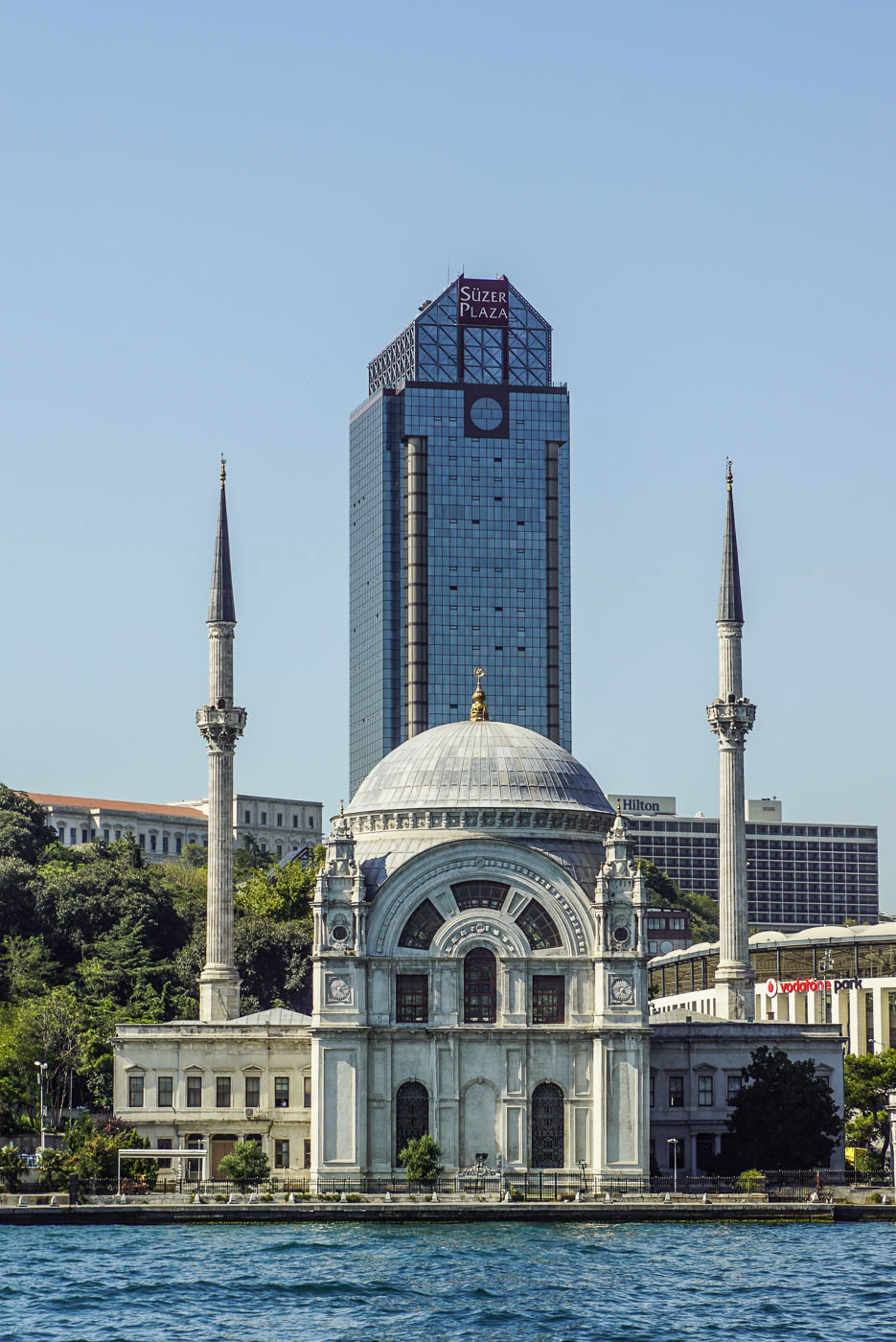 Blick auf eine Moschee vom Bosporus aus sie hat zwei Minarette und sieht relativ alt aus im Hintergrund erhebt sich ein Glas Hochhaus der Süzer Plaza.