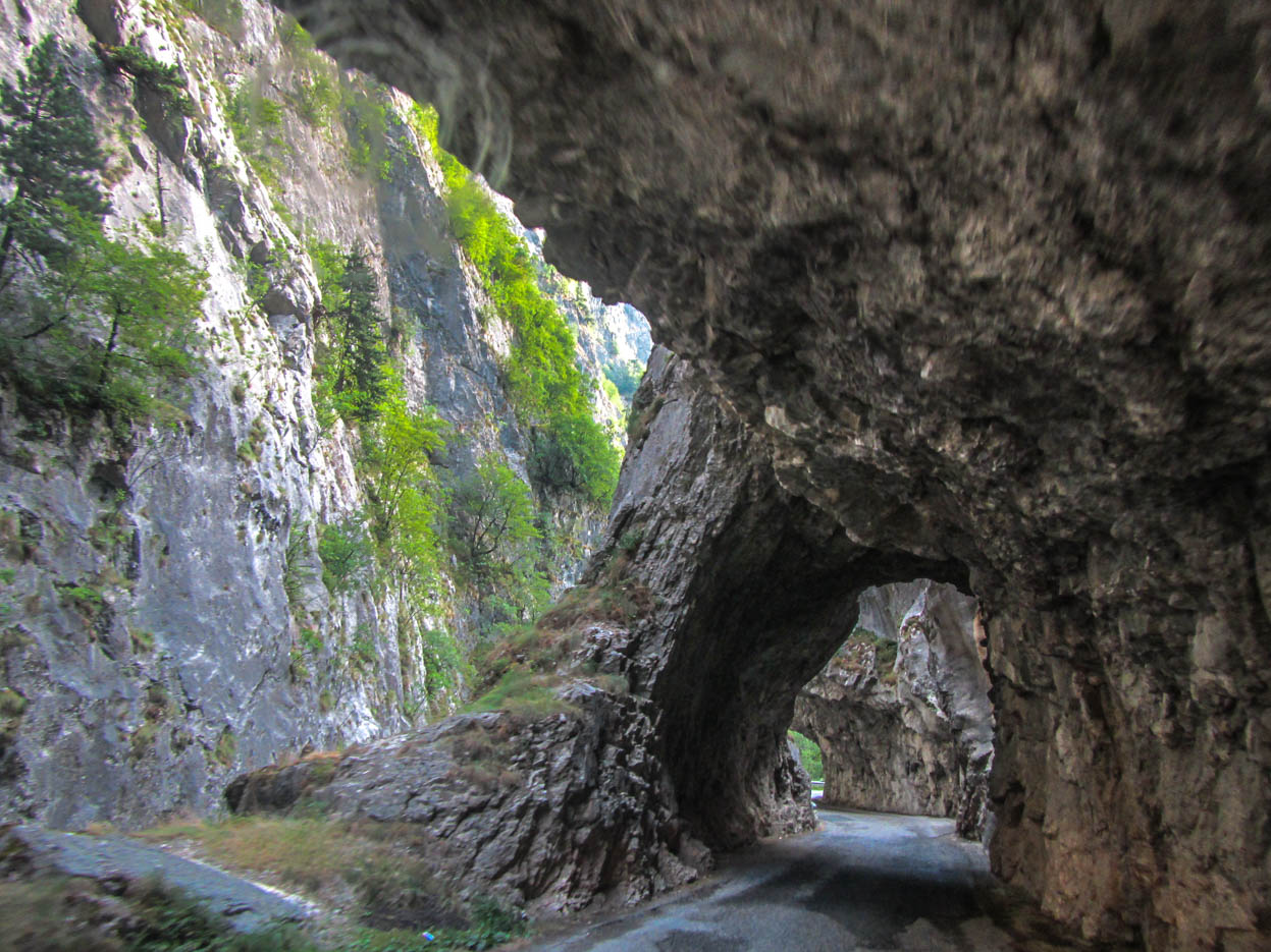 Es ist eine Straße zu sehen welche durch grob gehauene Tunnel durch einzelne Berg Überhänge verläuft.